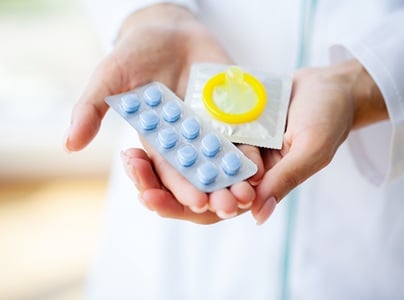 Eine &Auml;rztin, die eine Blisterpackung Viagra und ein Kondom in den H&auml;nden h&auml;lt.