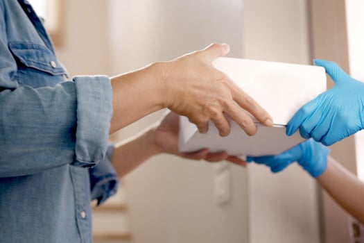 Un coursier remet une boîte dans un emballage discret à un homme.