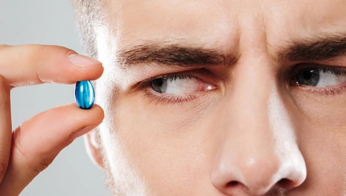 Un homme qui regarde d'un air suspicieux une capsule bleue